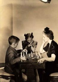 Portada:Plano general de Paul Rubinstein (perfil derecho) y Aniela Rubinstein (perfil izquierdo) jugando al ajedrez mientras Eva Rubinstein les observa