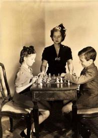 Portada:Plano general de Eva Rubinstein y Paul Rubinstein jugando al ajedrez mientras Aniela Rubinstein les observa