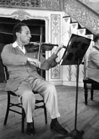 Portada:Plano general de Jascha Heifetz (perfil derecho) tocando el violín.