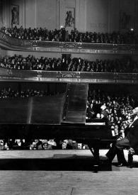 Portada:Plano general de Arthur Rubinstein (perfil izquierdo) sentado al piano, detrás el público aplaudiendo