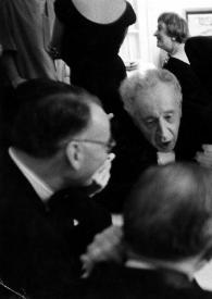 Portada:Plano medio de Jacques Février, Arthur Rubinstein, Juliette Achard y Marcel Achard, alrededor de una mesa, sentados charlando