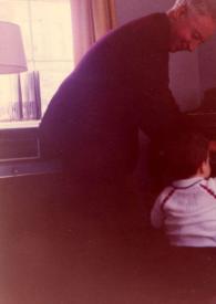 Portada:Plano general de Arthur Rubinstein (perfil derecho) tocando el piano de pie con Alexander Coffin Rubinstein (de espaldas) tocando también el piano