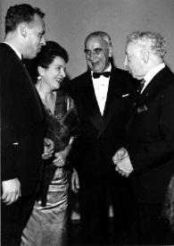 Portada:Plano general de tres personas charlando con Arthur Rubinstein (perfil derecho)