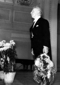 Portada:Plano general de Arthur Rubinstein (medio perfil izquierdo), de pie en el escenario, saludando al público