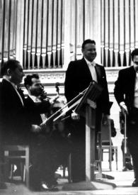 Portada:Plano general de Arthur Rubinstein aplaudiendo a un violonchelista en el escenario junto a la orquesta