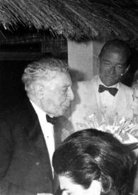 Portada:Plano medio de Arthur y Aniela Rubinstein apagando las velas de la tarta, rodeados de otras personas
