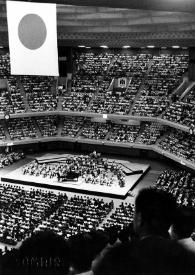 Portada:Plano general del Estadio Olímpico, al fondo el escenario en el que se encuentra, sentado al piano, Arthur Rubinstein. La bandera japonesa aparece en la parte superior