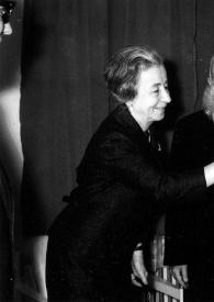 Portada:Plano medio de Arthur Rubinstein besando la mano de la mujer, detrás un hombre observándoles