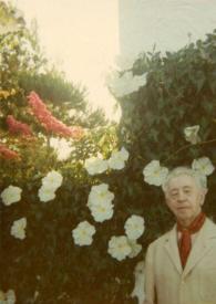 Portada:Plano medio de Arthur Rubinstein posando en el jardín delante de las flores de la luna