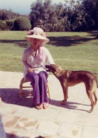 Portada:Plano general de Aniela Rubinstein sentada junto al jardín de la casa acariciando \"Café\" el perro de la raza pastor alemán