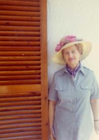 Portada:Plano medio de Aniela Rubinstein posando con un sombrero apoyada en una pared junto al jardín de la casa