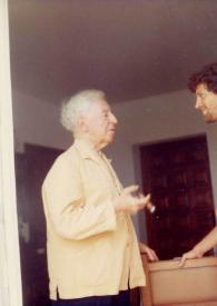 Portada:Plano general de Arthur Rubinstein (perfil derecho) con un puro en la mano derecha charlando con John Rubinstein (perfil izquierdo)