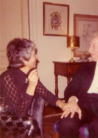 Portada:Plano medio de Karin Falencki (perfil derecho) sentada en un sillón cogiendo la mano a Arthur Rubinstein sentado en una silla a su lado con un puro en la mano izquierda