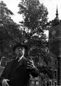 Portada:Plano medio de Arthur Rubinstein, gesticulando con las manos mientras  posa delante de una torre antigua con un reloj