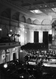 Portada:Plano general de la sala de conciertos, en el centro del escentario Arthur Rubinstein sentado al piano, detrás la orquesta. El escenario está presidido por un gran órgano.
