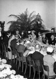 Portada:Plano general de una de las mesas de la comida: Arthur Rubinstein (de espaldas) sentado junto a otras personas