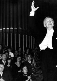 Portada:Plano general de Arthur Rubinstein saludando en el escenario, con un brazo en alto, detrás el público aplaudiendo