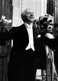 Portada:Plano general de Arthur Rubinstein saludando en el escenario con los brazos abiertos, al fondo un fotógrafo se dispone a fotografiarle