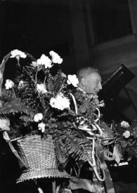 Portada:Plano medio de Arthur Rubinstein saludándo al público, rodeado de flores que un hombre desde la parte baja del escenario va entregándole