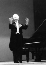 Portada:Plano general de Arthur Rubinstein de pie junto al piano con los brazos alzados, saludando al público