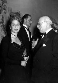 Portada:Plano general de Aniela Rubinstein y Sol Hurok (perfil izquierdo) charlando, detrás Basil Rathbone.
