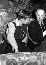 Portada:Plano general de Paul Rubinstein (perfil derecho), Arthur Rubinstein saludando a la cámara y un hombre sentados en unas butacas