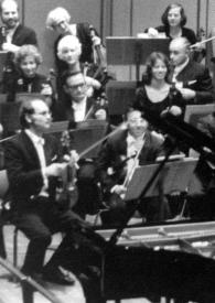 Portada:Plano general de la orquesta, delante Arthur Rubinstein estrechando la mano al director de la orquesta