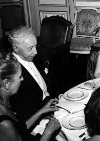 Portada:Plano medio de una mujer, Arthur Rubinstein, una mujer y André Jeanneret sentados en la mesa charlando