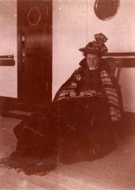 Portada:Plano general de la Señora de Rosentower sentada en una mecedora con una manta en las rodillas, posando en la cubierta del barco