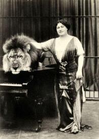 Portada:Plano general de un león encima de un piano y una mujer posando