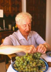 Portada:Plano medio de Arthur Rubinstein sentado en una mesa cogiendo unas uvas de un recipiente