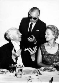 Portada:Plano medio de Arthur Rubinstein, Frederic Rand Mann (de pie) y Aniela Rubinstein sentados en la mesa