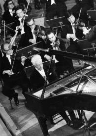 Portada:Plano general de Arthur Rubinstein sentado al piano, Bernard Haitink (de espaldas), con la batuta en la mano derecha, dirigiendo a la orquesta, que está situada detrás de ellos