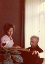 Portada:Plano medio de Alina y John de pie a cada lado del piano observando a Arthur Rubinstein sentado al piano